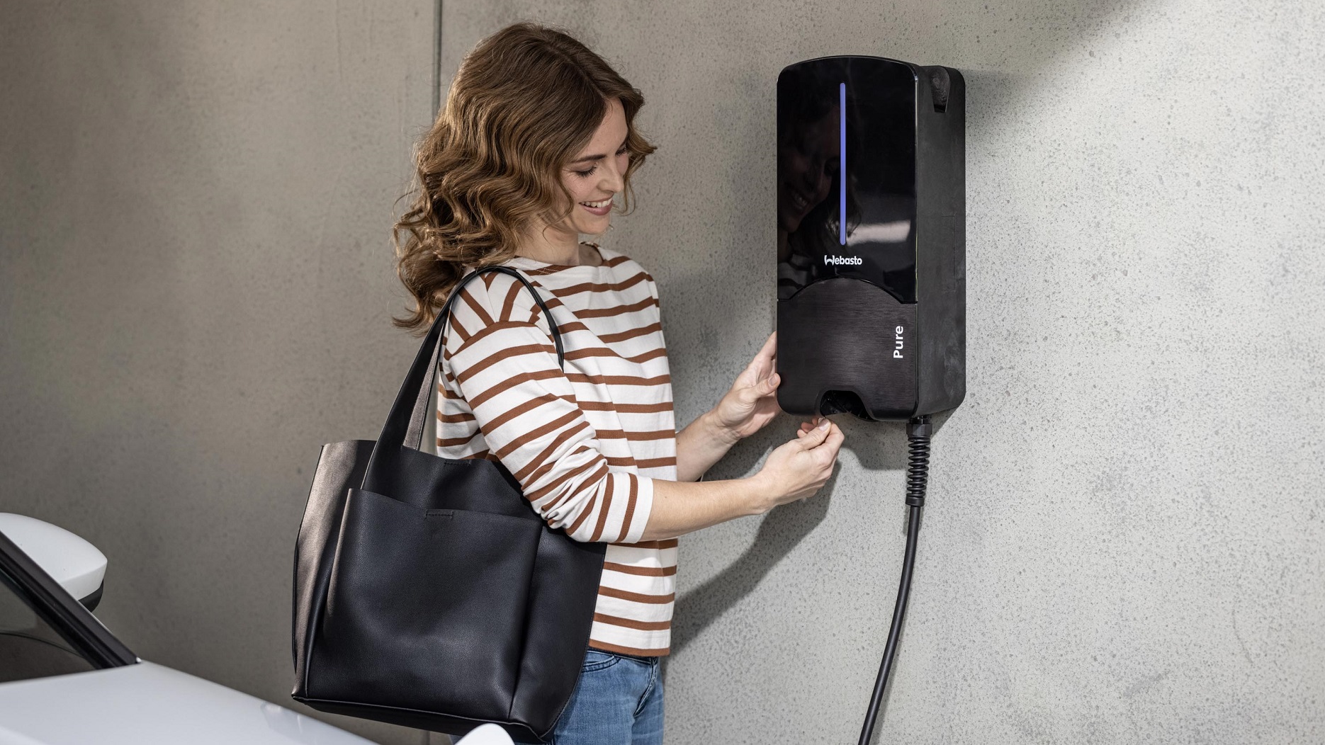 Person verbindet ein Elektrofahrzeug mit einer Webasto-Ladestation.