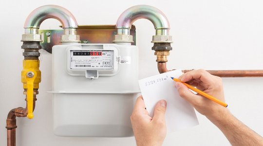 Gaszähler Gaszähler mit Händen die den Zählerstand notieren