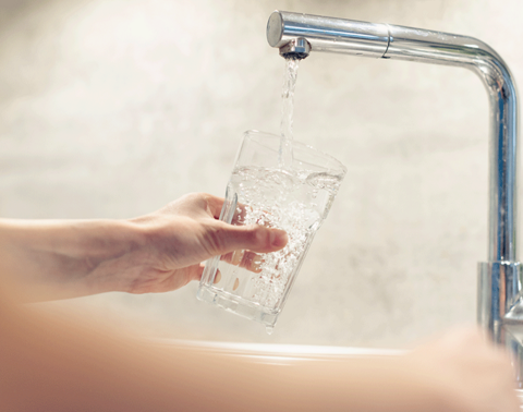 Wasser wird in ein Glas aus dem Wasserhahn gefüllt