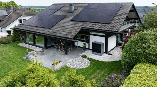 Private Photovoltaikanlage Haus mit Solarpanels auf dem Dach, Garten und möblierter Terrasse.