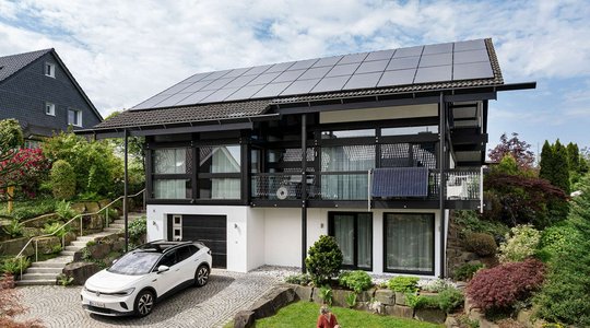 Balkonkraftwerk am Haus Modernes Haus mit Solardach und E-Auto in Einfahrt, umgeben von Garten und Nachbarhaus